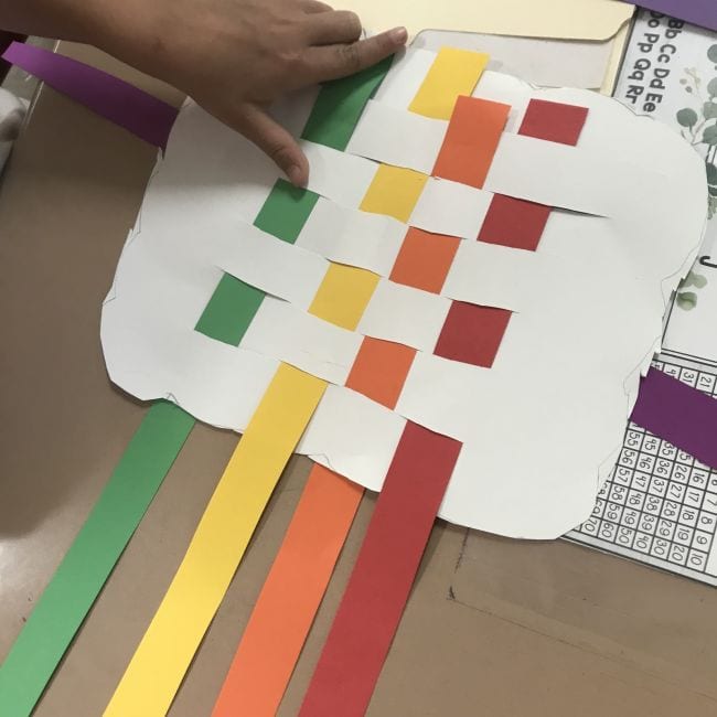 Rainbow paper woven through a white paper cloud